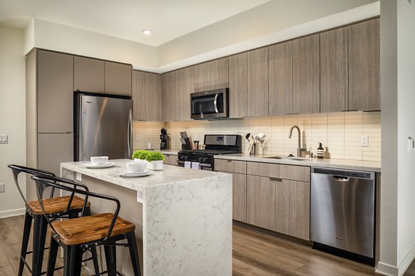 Kitchen with modern appliances and sleek cabinetry at One Paseo Living Apartments