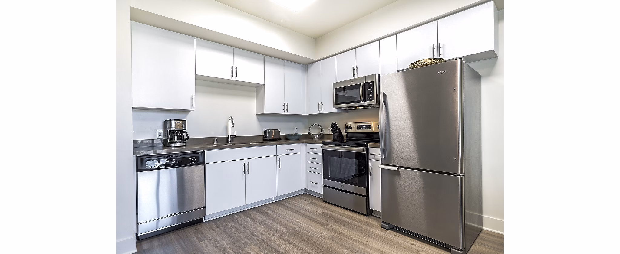 Modern kitchen with stainless steel appliances and granite countertops at CC Tan Center Apartments