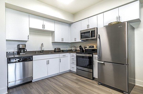 Modern kitchen with stainless steel appliances and granite countertops at CC Tan Center Apartments