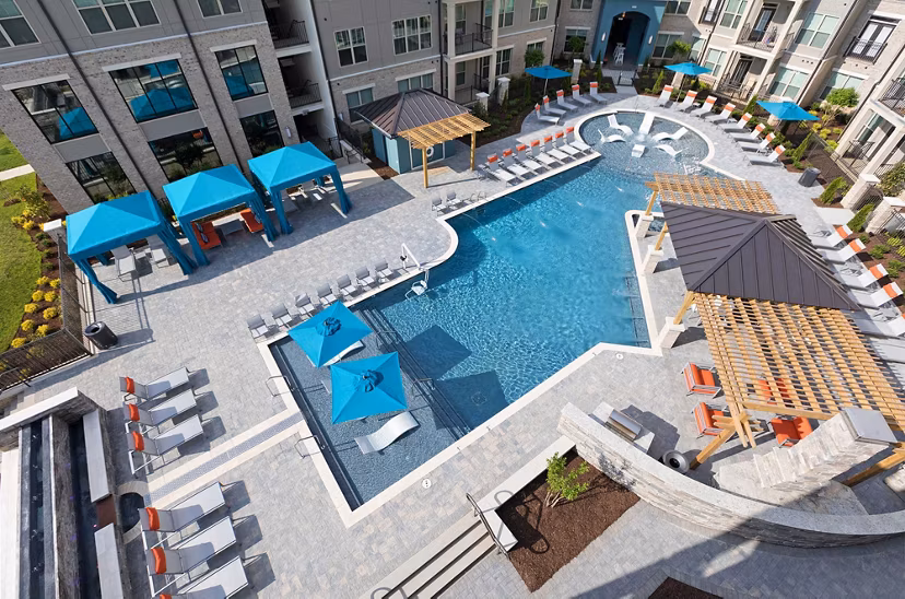 Resort-style pool surrounded by lush landscaping at Avia Apartments