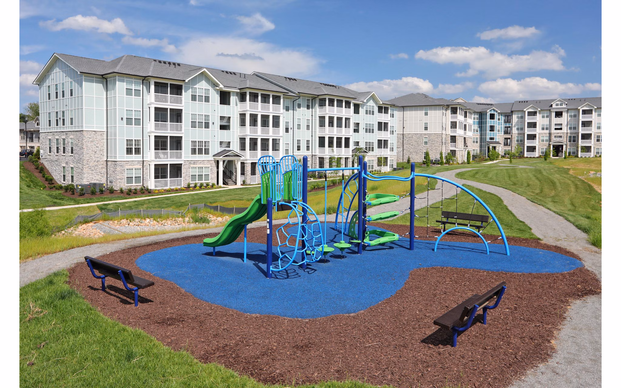 Colorful playground surrounded by trees at Avia Apartments, offering a fun and safe environment for families