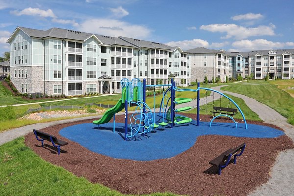 Colorful playground surrounded by trees at Avia Apartments, offering a fun and safe environment for families