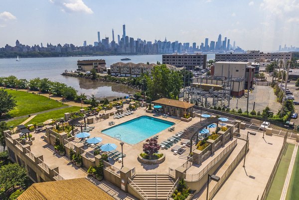 Pool with sleek lounge chairs at Half Moon Harbour Apartments offering luxury waterfront views