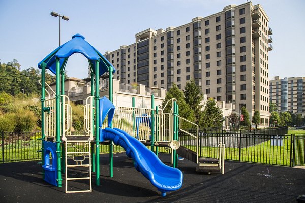 Modern playground at Half Moon Harbour Apartments with slides and swings overlooking scenic waterfront