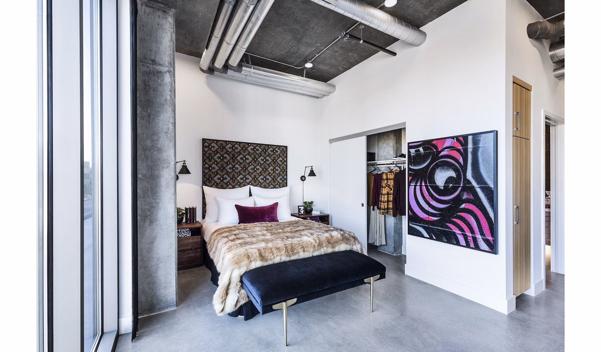 Cozy bedroom featuring modern decor and ample natural light at AMP Lofts Apartments