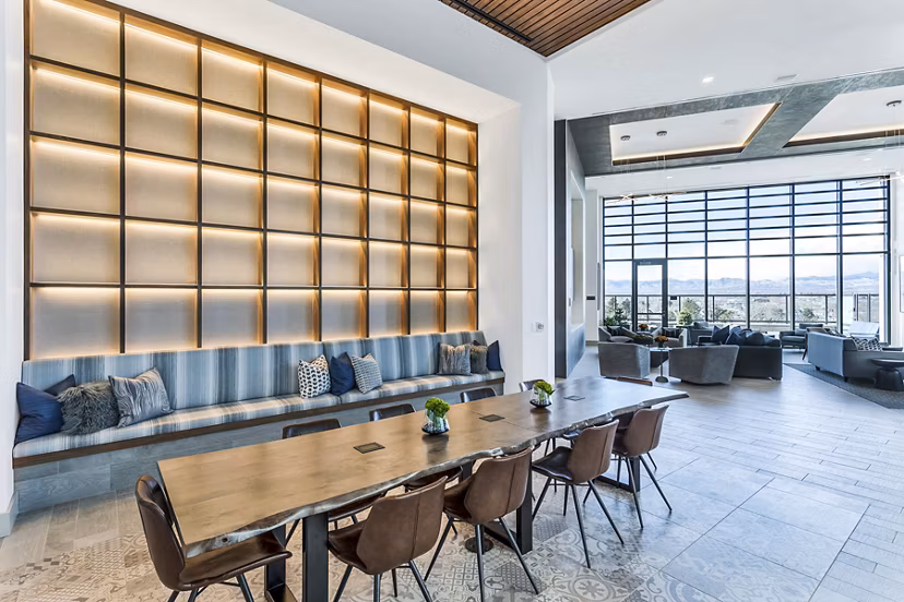 Parq on Speer Apartments: Modern lounge area with long table, chairs, and large windows in luxury setting