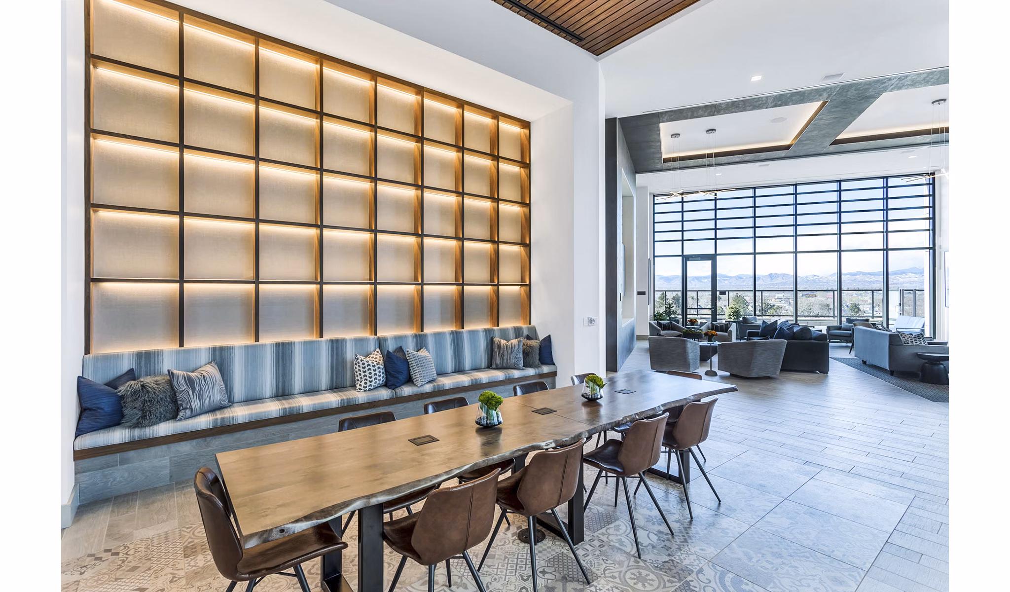 Parq on Speer Apartments: Modern lounge area with long table, chairs, and large windows in luxury setting