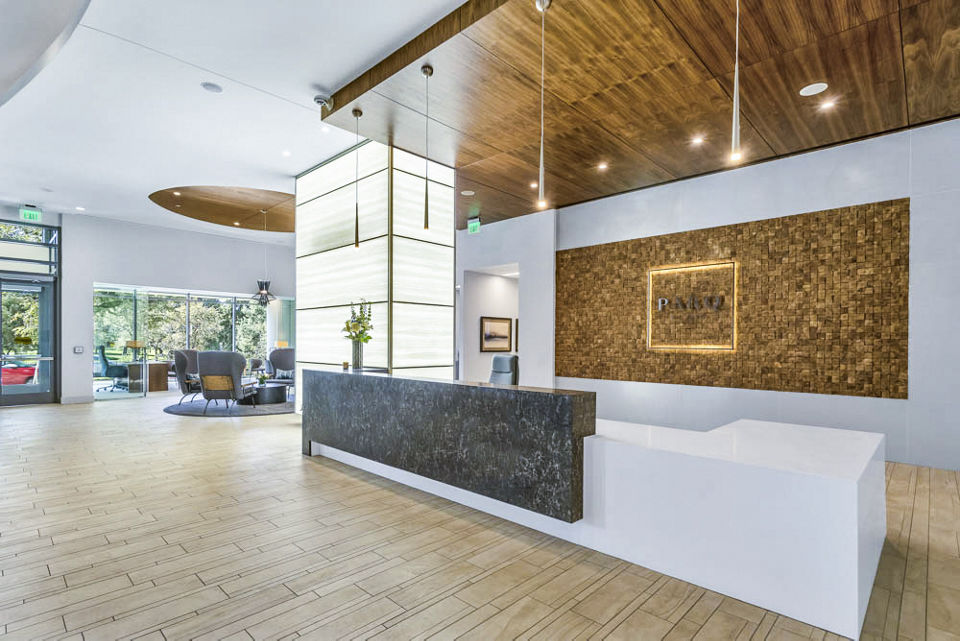 Spacious, stylish lobby with wood accents and large reception desk at Parq on Speer Apartments in Denver