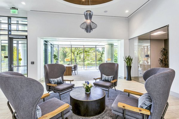 Bright and inviting lobby with gray chairs, round table, and expansive windows at Parq on Speer Apartments in downtown Denver
