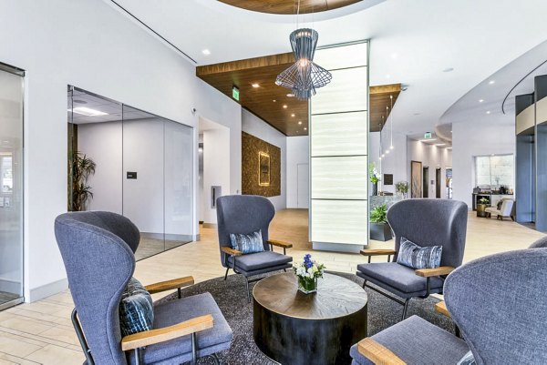 Contemporary lobby with gray chairs, round table, and artistic lighting at Parq on Speer Apartments A welcoming luxury space in downtown Denver