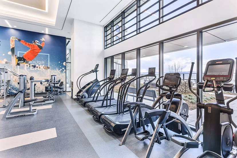 Bright gym equipped with cardio machines and motivational wall art at Parq on Speer Apartments