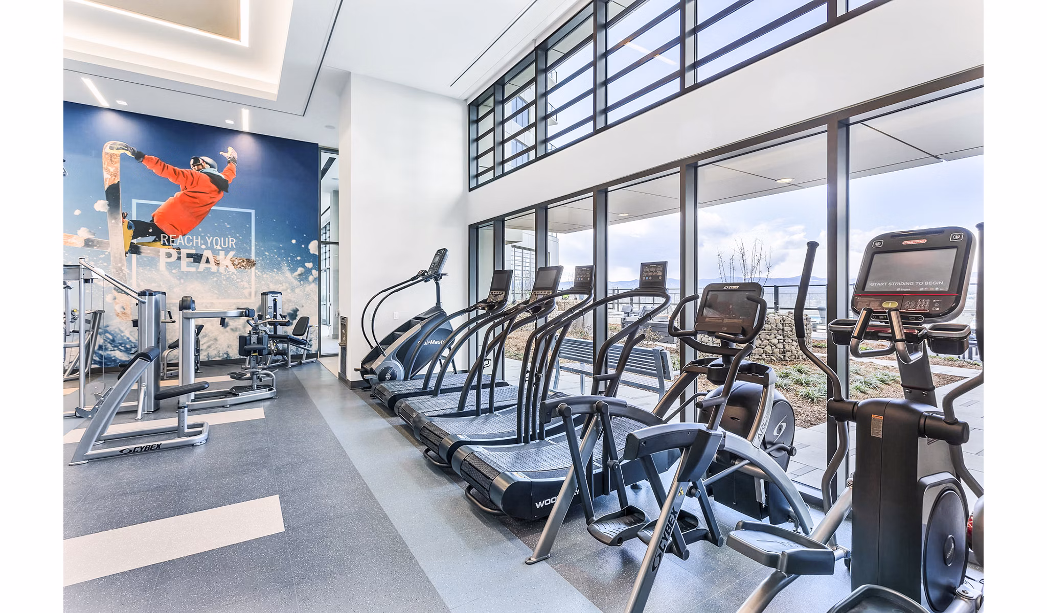 Bright gym equipped with cardio machines and motivational wall art at Parq on Speer Apartments