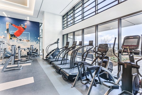Bright gym equipped with cardio machines and motivational wall art at Parq on Speer Apartments