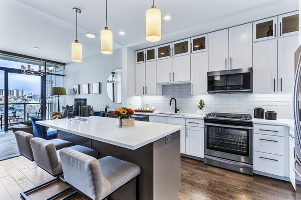 Modern kitchen with island, pendant lights, and stunning city views at Parq on Speer Apartments in Greystar's luxury community