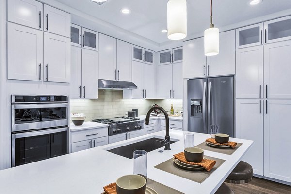 Sleek kitchen featuring white cabinets and stainless steel appliances with an island at Parq on Speer Apartments