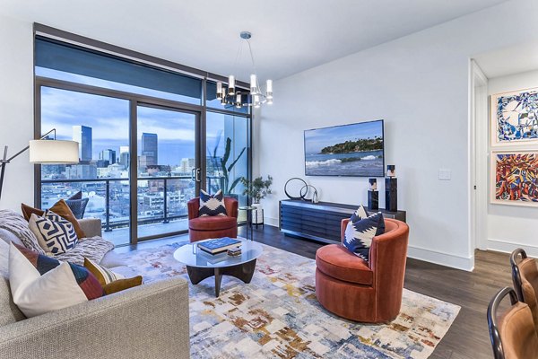 Stylish living room with vibrant decor and city skyline view at Parq on Speer Apartments with balcony
