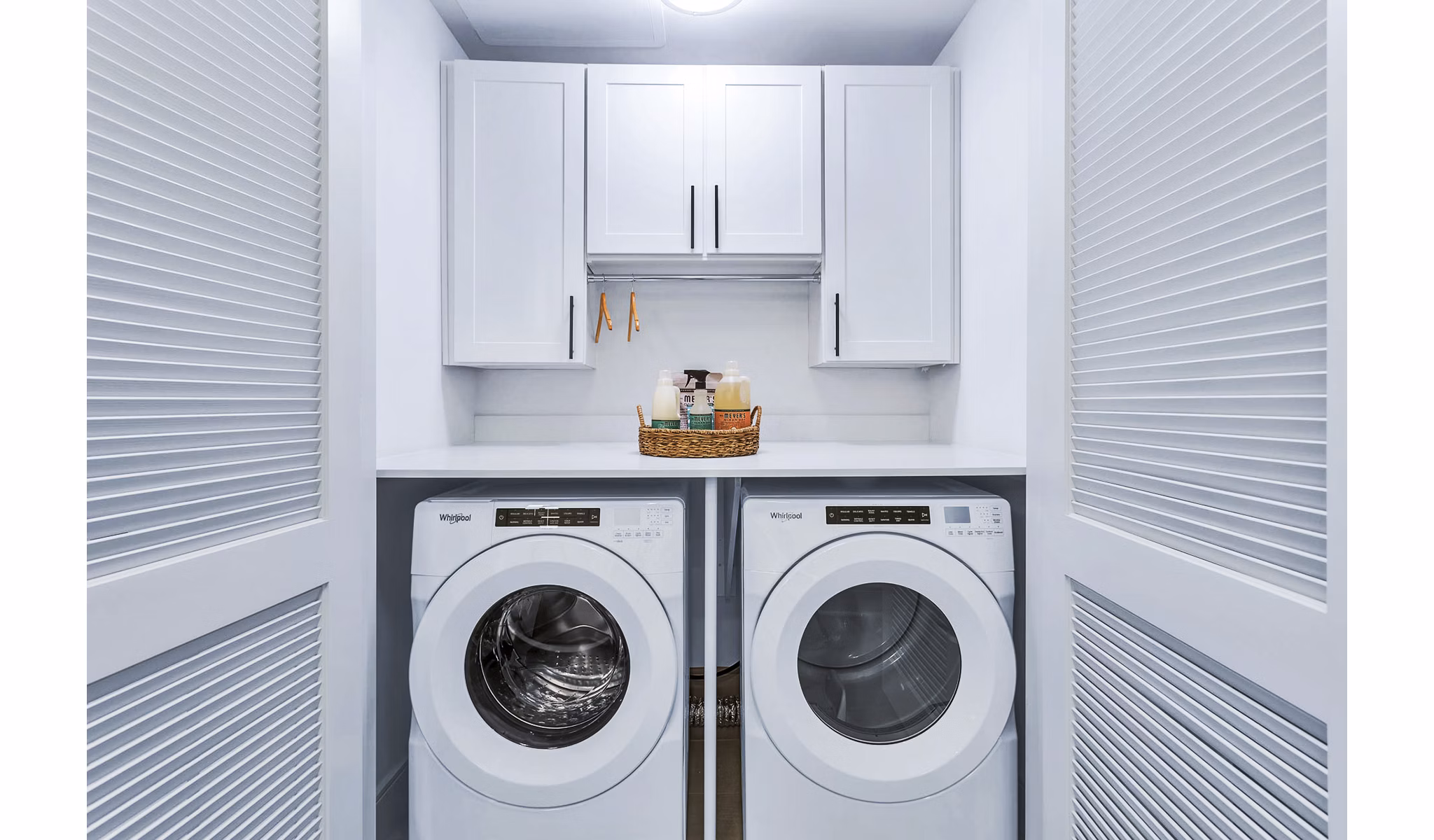 Compact laundry room featuring washer, dryer, and storage cabinets in Parq on Speer Apartments, luxury living in Denver