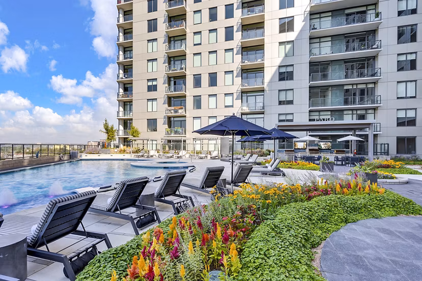 Parq on Speer: Luxury apartment building with pool, lounge chairs, and vibrant flowers in Denver