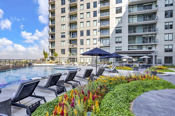 Parq on Speer: Luxury apartment building with pool, lounge chairs, and vibrant flowers in Denver