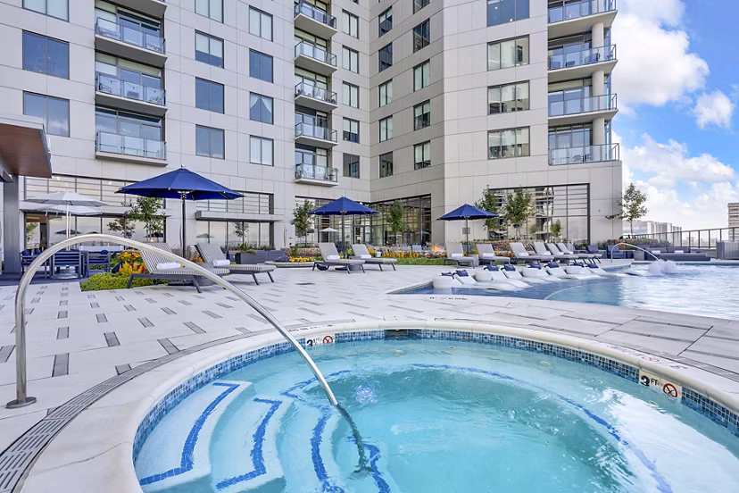 Parq on Speer: Luxury apartment building with pool, hot tub, lounge chairs, and umbrellas in a premium Denver location