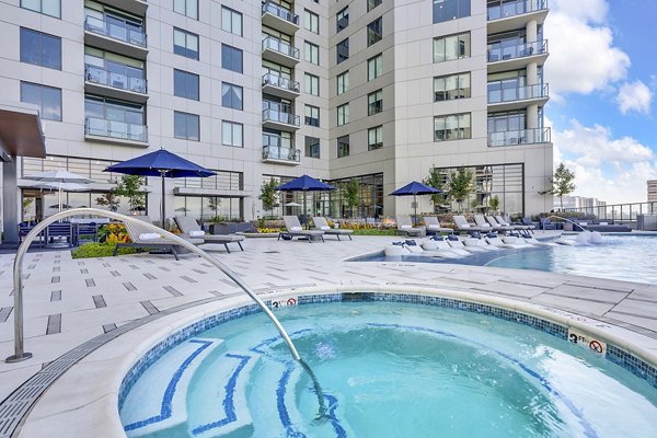 Parq on Speer: Luxury apartment building with pool, hot tub, lounge chairs, and umbrellas in a premium Denver location