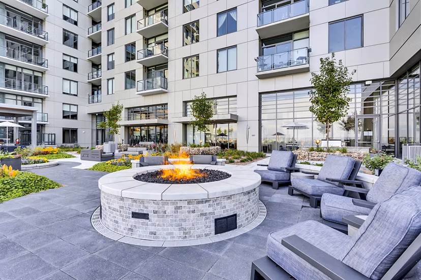 Outdoor patio with fire pit and seating area at Parq on Speer Apartments, featuring luxury apartment building backdrop