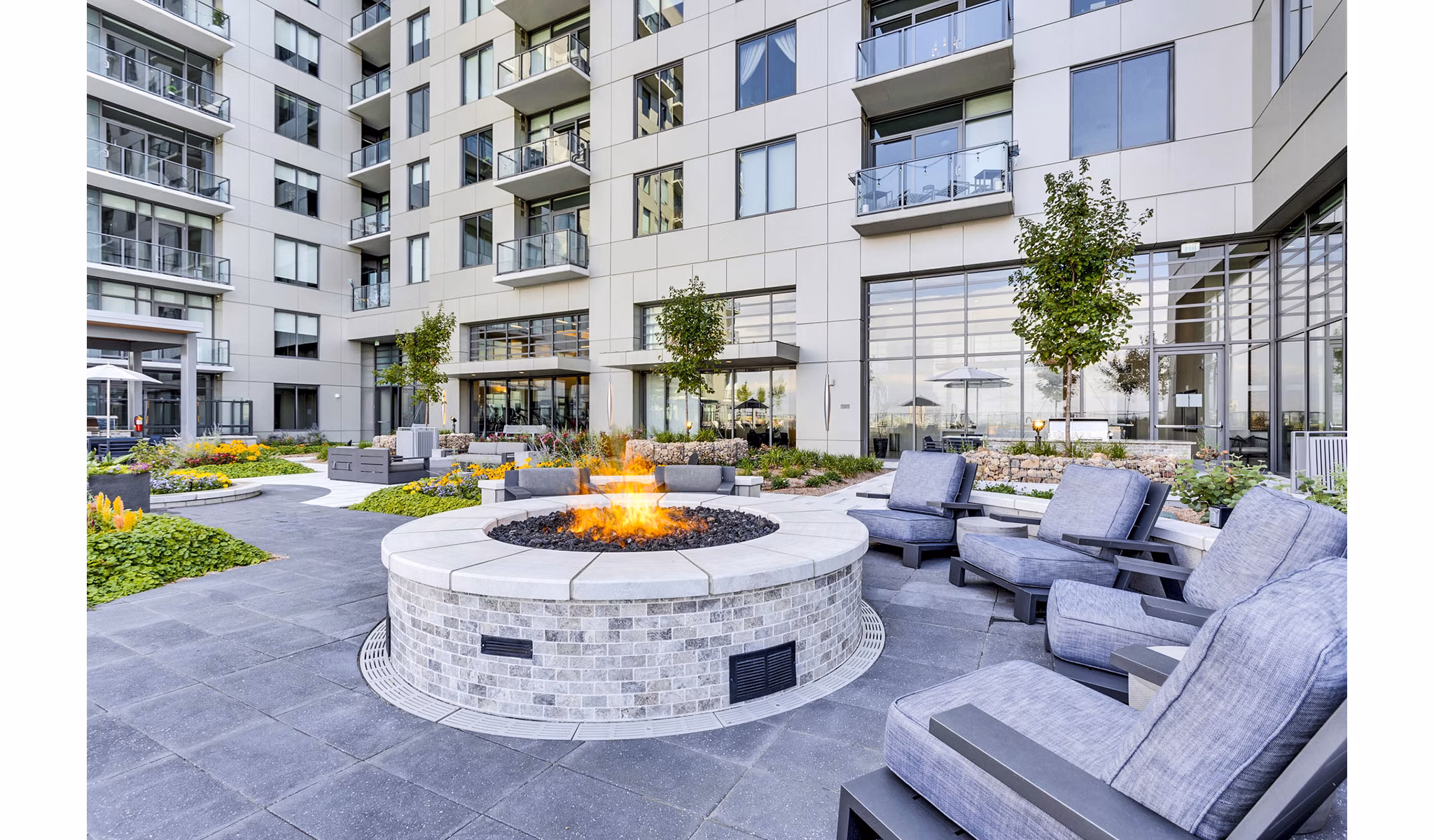 Outdoor patio with fire pit and seating area at Parq on Speer Apartments, featuring luxury apartment building backdrop