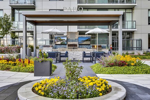 Modern outdoor patio with seating, umbrellas, and vibrant flowers at Parq on Speer Apartments, a luxury  property
