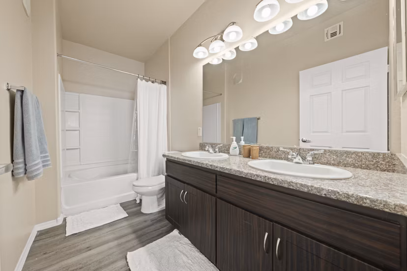 Modern bathroom with granite countertops and large mirror at Bella Mirage Apartments
