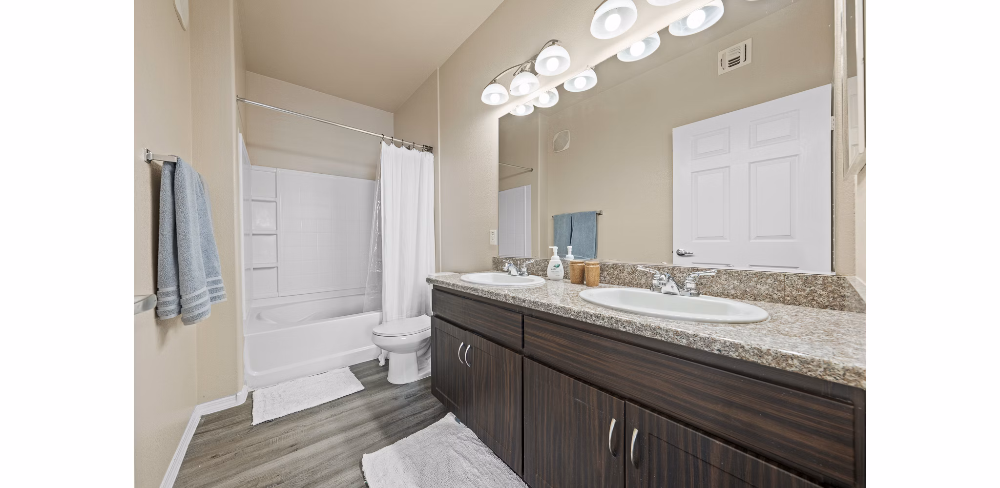 Modern bathroom with granite countertops and large mirror at Bella Mirage Apartments