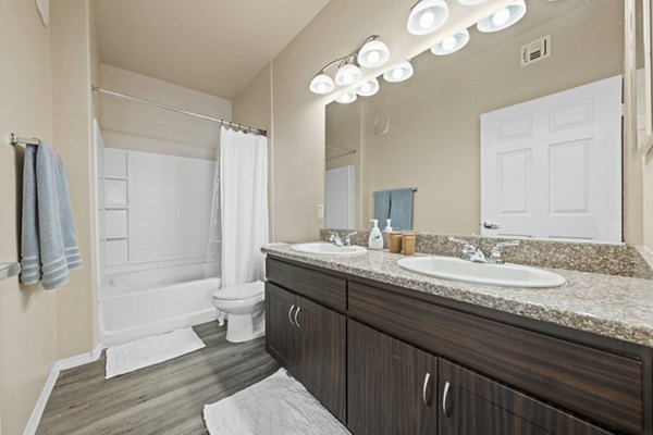 Modern bathroom with granite countertops and large mirror at Bella Mirage Apartments