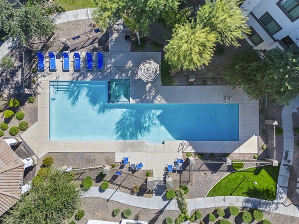 Resort-style pool with lounge chairs at Bella Mirage Apartments, offering luxury amenities in a serene setting