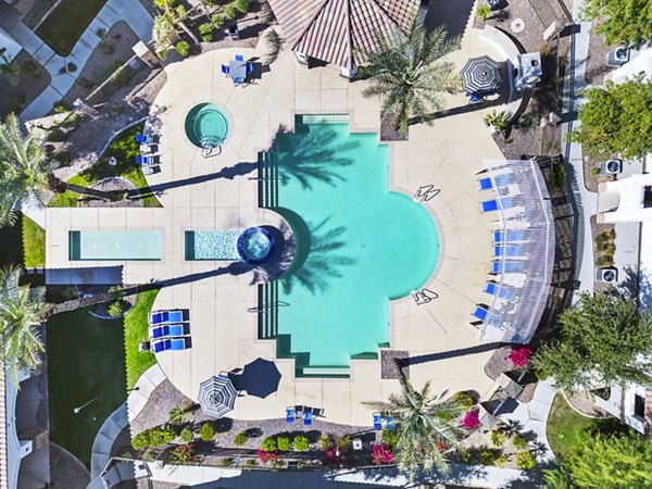 Outdoor pool with sun loungers at Bella Mirage Apartments, offering relaxation and luxury living in Las Vegas