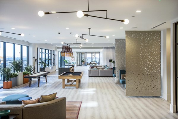 Modern lounge area with open-concept design, seating, and a pool table in luxury apartments