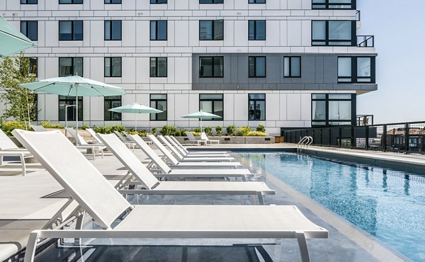Sunlit lounge chairs by the pool at 500 Ocean Ave Apartments, perfect for relaxation with luxury amenities for a resort-style experience