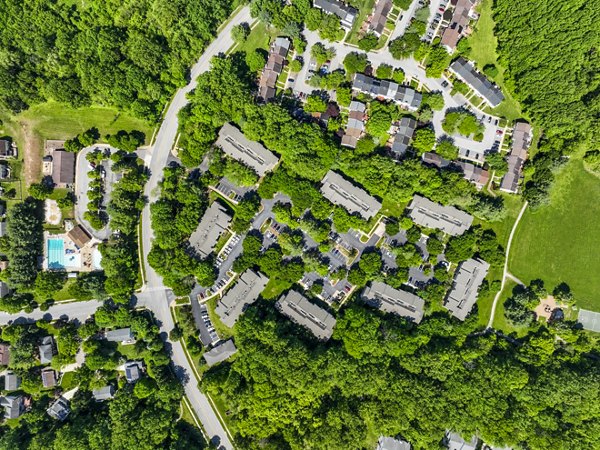 Aerial view of luxury apartments surrounded by lush greenery and roads in a vibrant residential neighborhood