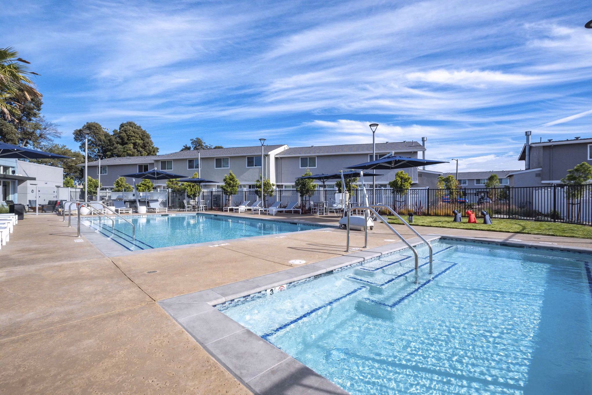 Relaxing pool area at Admirals Cove Apartments featuring lounge chairs and lush landscaping, perfect for unwinding in a serene environment
