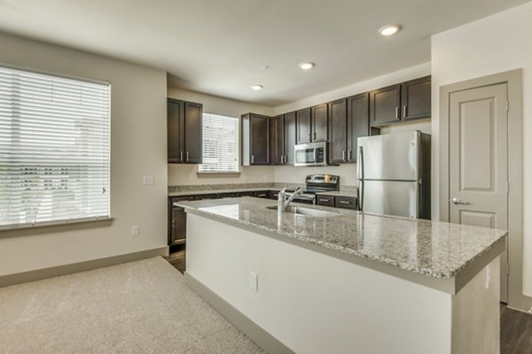 Modern kitchen with stainless steel appliances and granite countertops at The Grayson Apartments