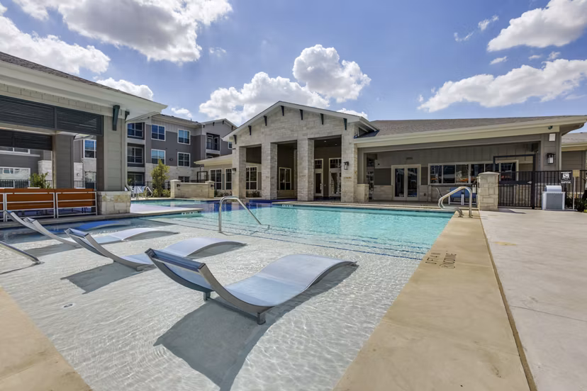Resort-style pool area with lounge chairs at The Grayson Apartments, offering a luxury lifestyle experience in a serene setting