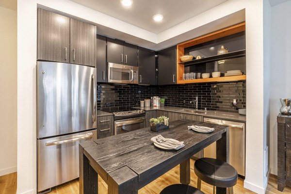 Modern kitchen with sleek cabinetry and stainless steel appliances at Pike Motorworks Apartments in Seattle, offering luxury living experiences