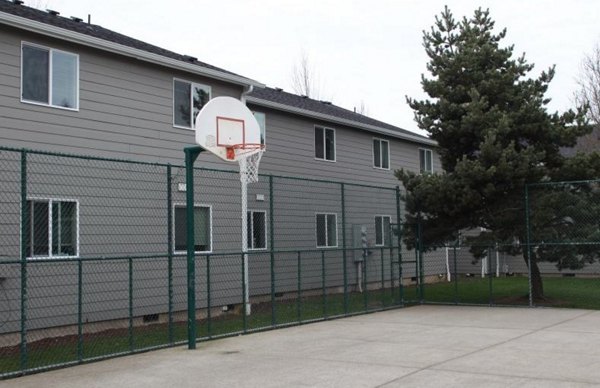 Outdoor sport court at Village East Apartments with basketball hoops and tennis markings, offering recreational amenities for residents
