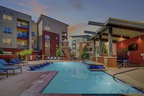 Modern outdoor pool at Mason at Alameda Station Apartments, featuring lounge chairs and umbrellas for relaxation