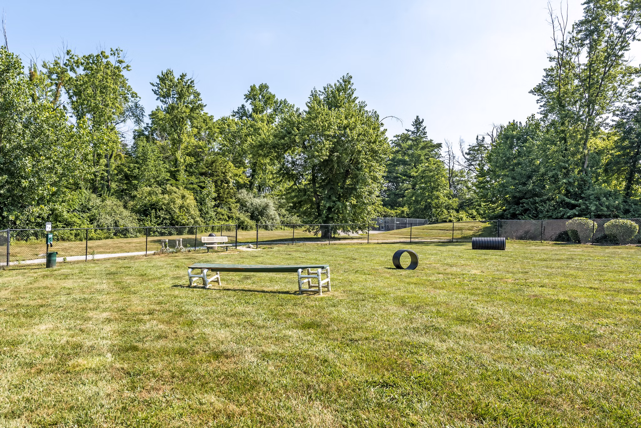 Dog park at Copper Chase at Stones Crossing Apartments featuring agility equipment and green spaces for pets to enjoy