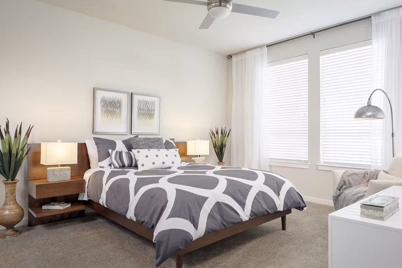 Bedroom with modern decor and large windows at The Upton at Longhorn Quarry Apartments