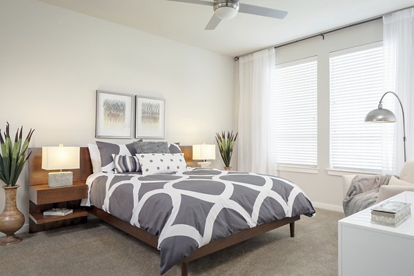 Bedroom with modern decor and large windows at The Upton at Longhorn Quarry Apartments