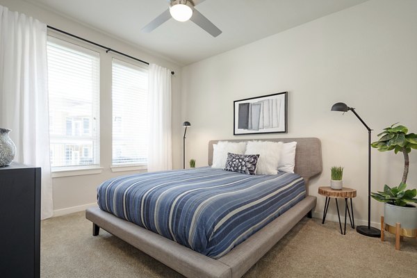 Bedroom with elegant furnishings and neutral tones at The Upton at Longhorn Quarry Apartments