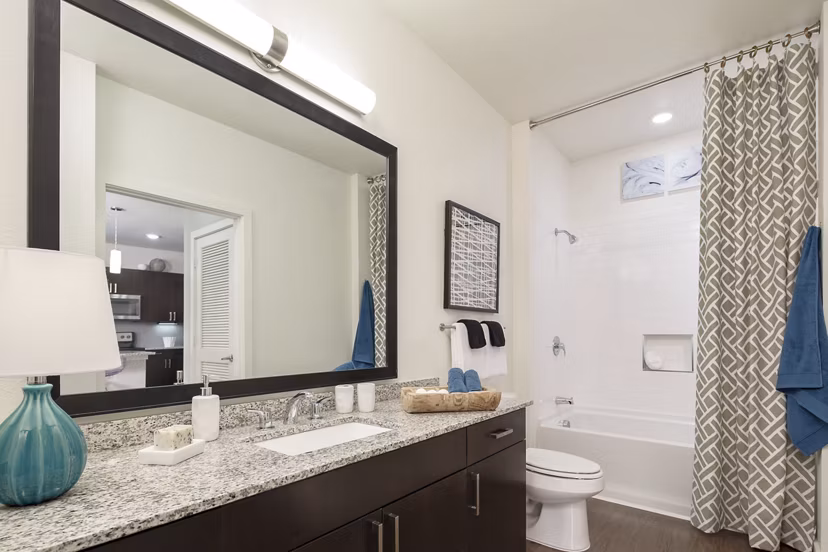 Modern bathroom featuring sleek fixtures and large mirror in The Upton at Longhorn Quarry Apartments