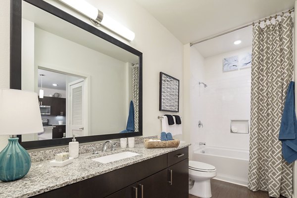 Modern bathroom featuring sleek fixtures and large mirror in The Upton at Longhorn Quarry Apartments