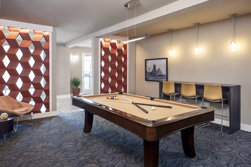 Game room showcasing a pool table, large-screen TV, and lounge seating at The Upton at Longhorn Quarry Apartments in San Antonio