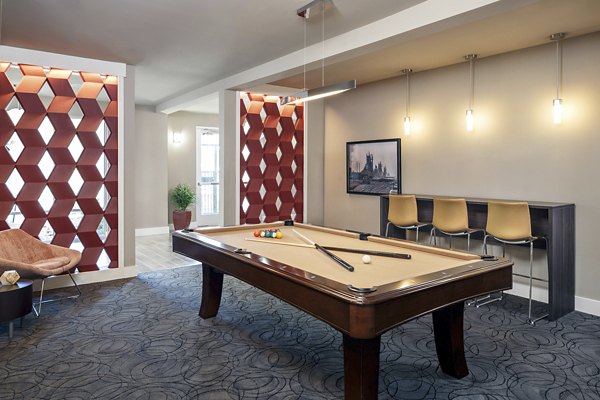 Game room showcasing a pool table, large-screen TV, and lounge seating at The Upton at Longhorn Quarry Apartments in San Antonio
